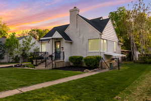 View of front of house with a front lawn, a chimney, brick siding, and a shingled roof