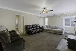 Living room featuring light colored carpet, a ceiling fan, and ornamental molding