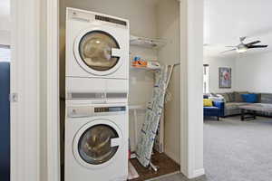 Laundry area with stacked washer / dryer, shelving and ironing board