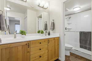 Bathroom featuring double vanity, a stall shower, and dark wood-style floors