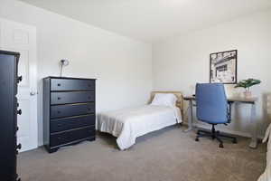 Bedroom featuring light colored carpet and an office area