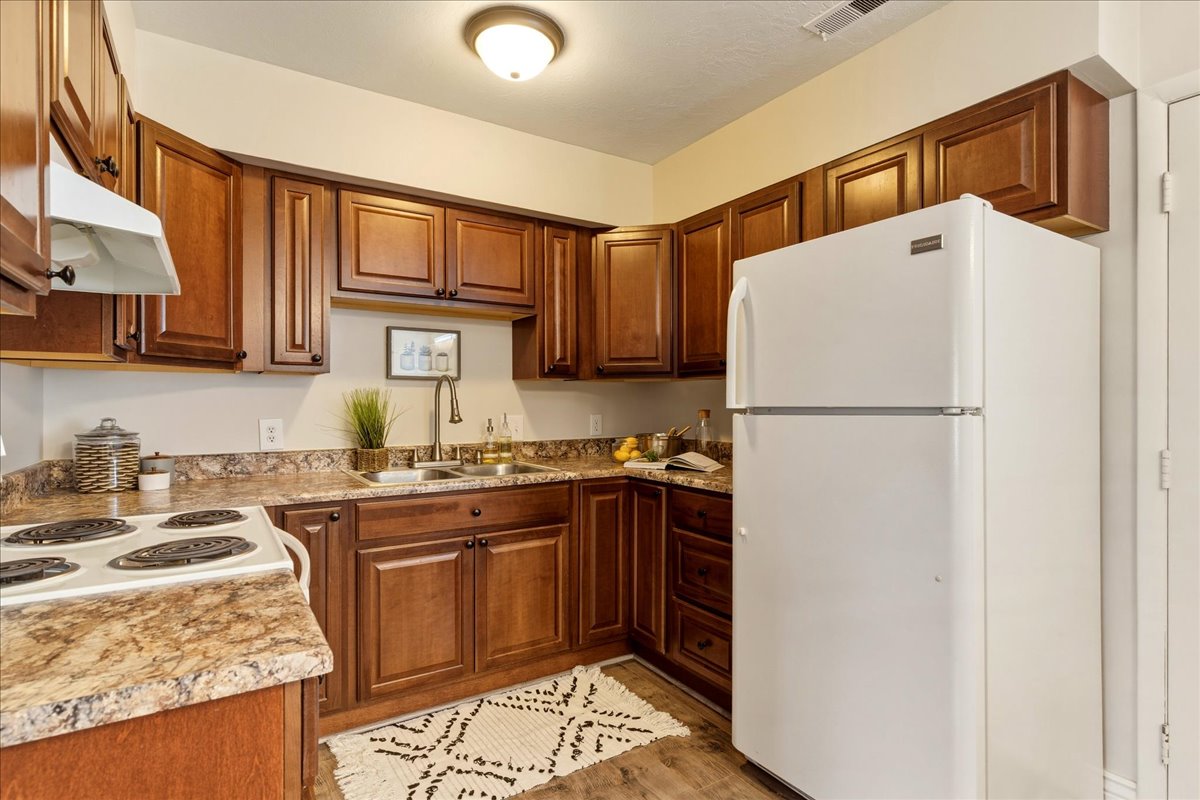 Kitchen featuring white appliances, wood finish cabinetry, light countertops, and light wood-style floors
