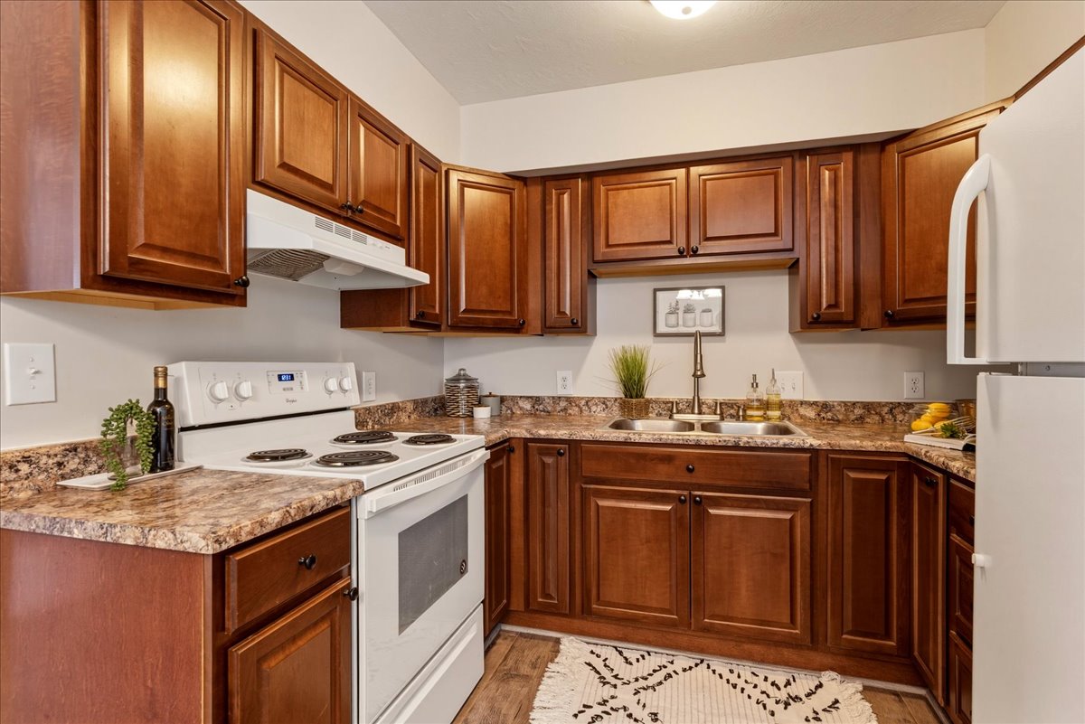 Kitchen featuring white appliances, wood finish cabinetry, and light wood-style flooring