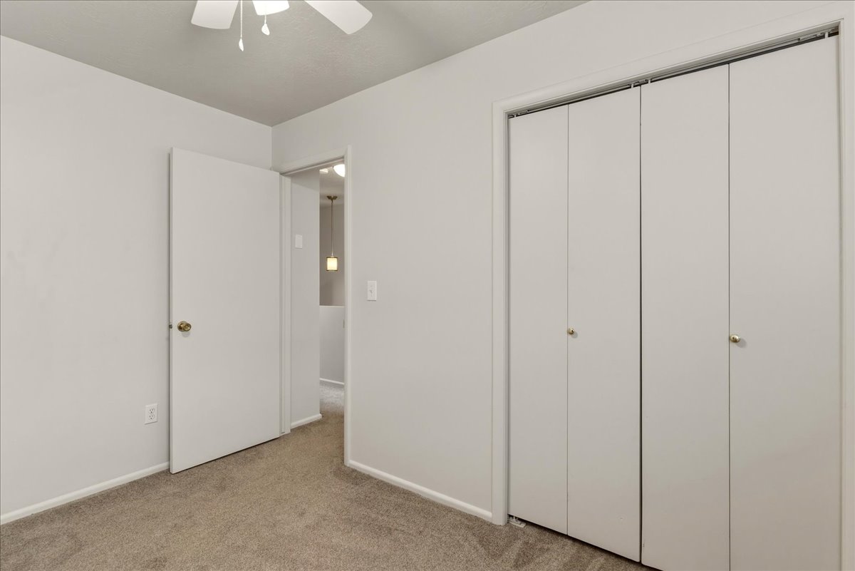 Unfurnished bedroom with light colored carpet, a closet, and ceiling fan