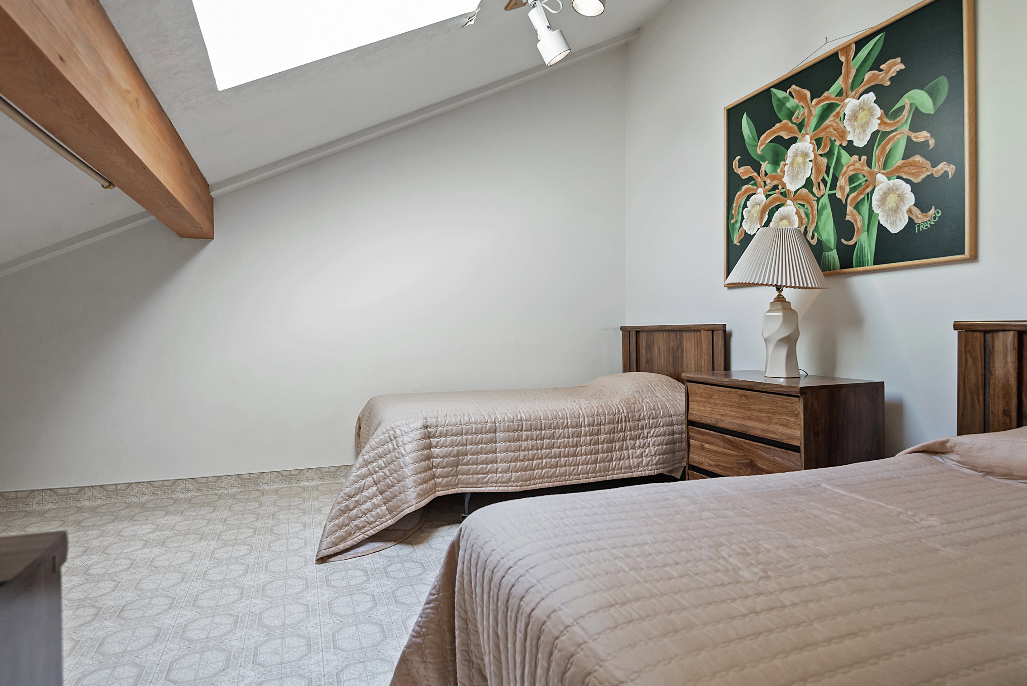 Bedroom with vaulted ceiling with beams and a skylight