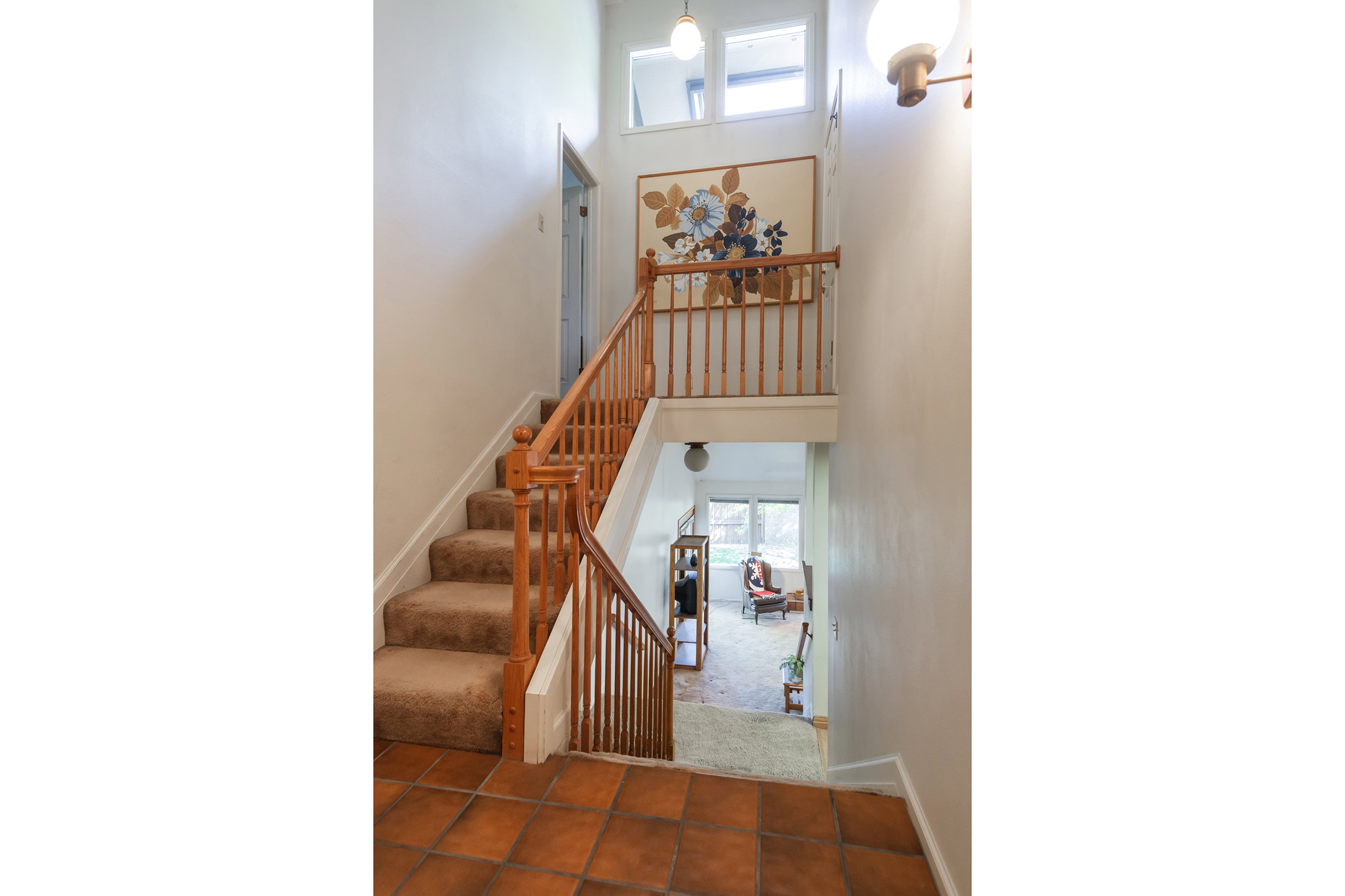 Staircase featuring a high ceiling, carpet flooring, and tile patterned flooring