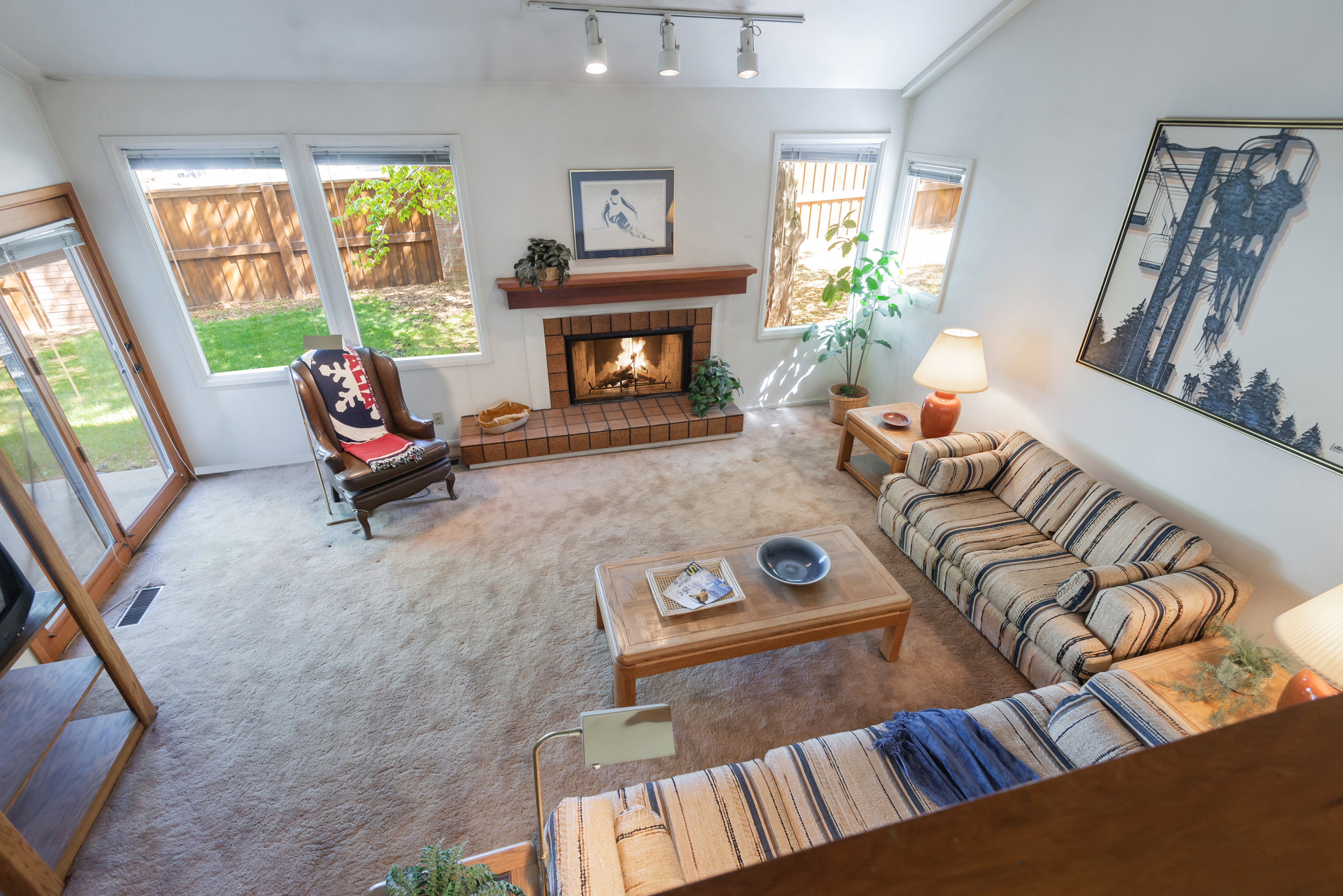 Carpeted living room featuring a tiled fireplace and rail lighting