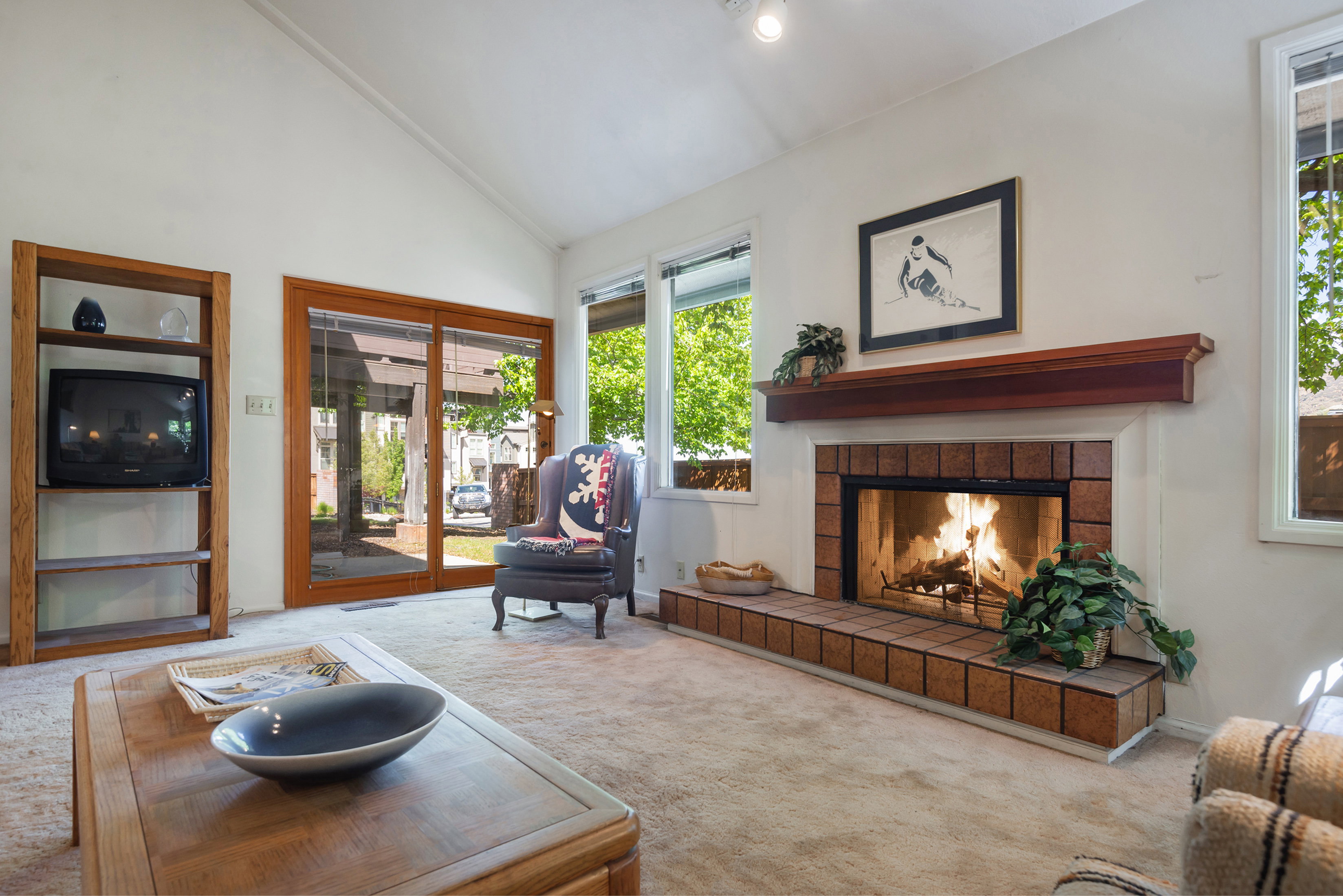 Carpeted living room featuring a tile fireplace and vaulted ceiling