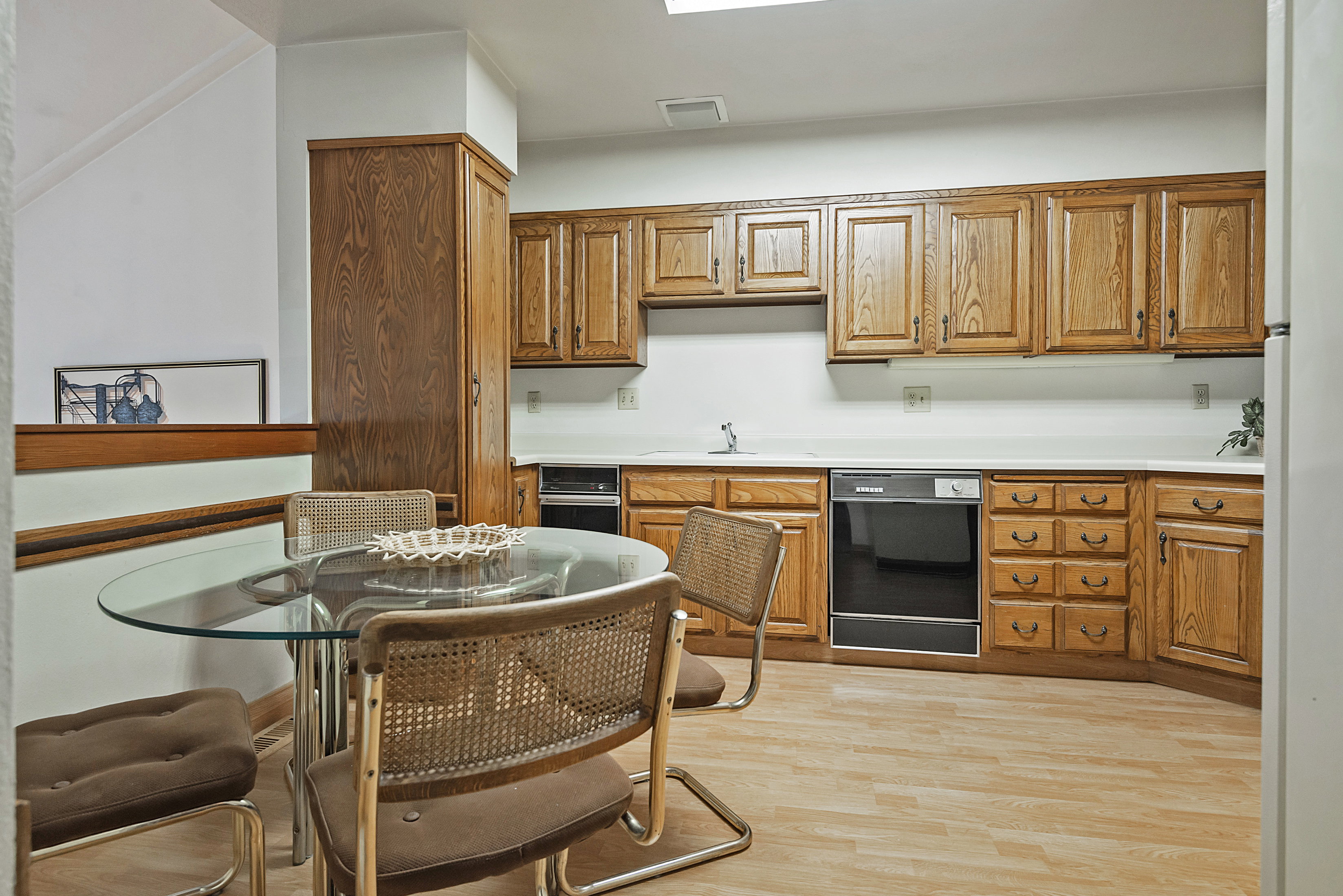 Kitchen with light wood-style flooring, light countertops, wood finish cabinets, and black dishwasher