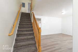Staircase with wood finished floors, and textured ceiling