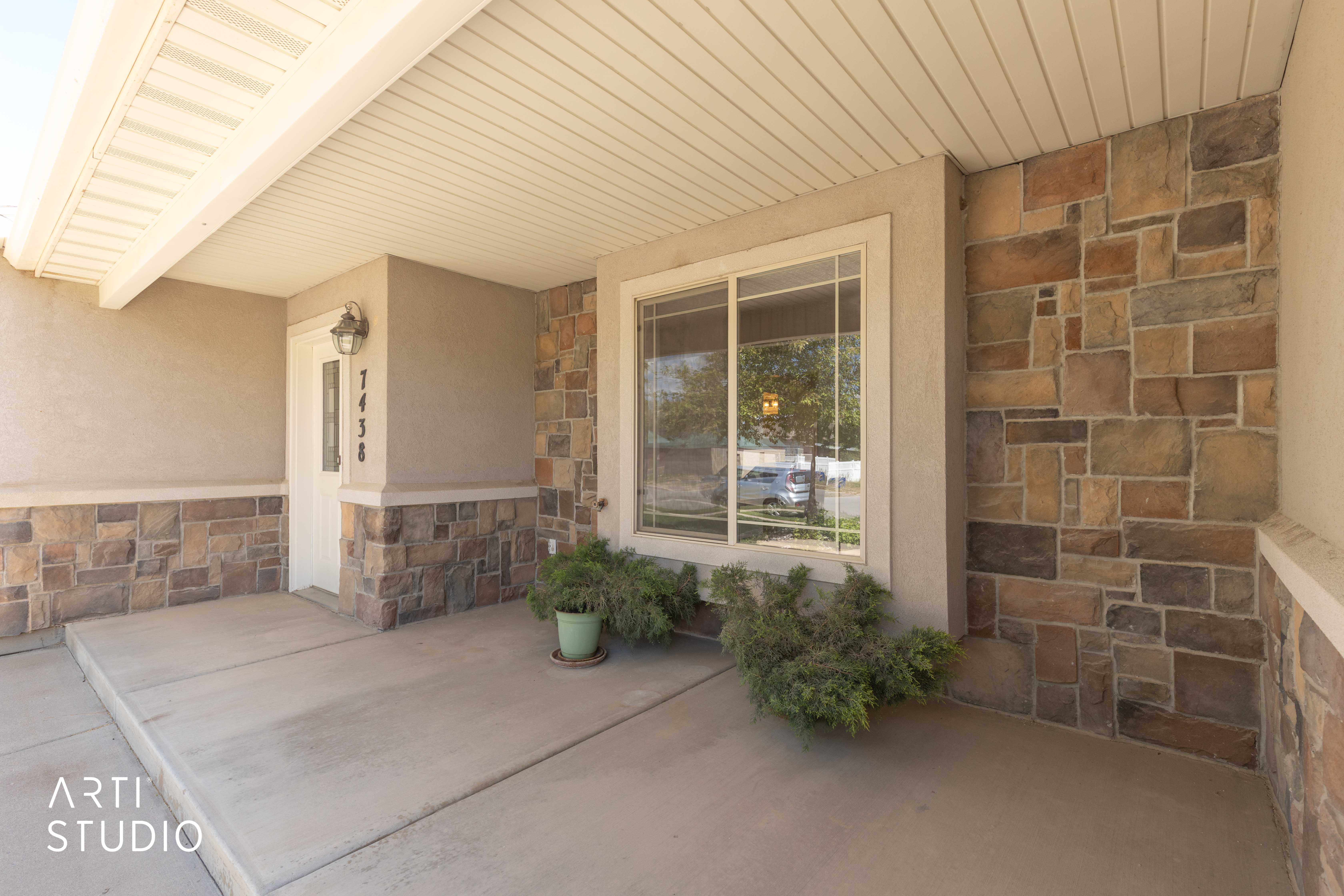Property entrance featuring stone siding, a porch, and stucco siding