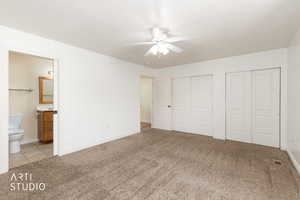 Bedroom with two closets, light carpet, connected bathroom, and a ceiling fan