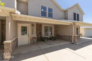 View of front of property featuring stone siding, stucco siding, and covered porch