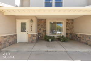 Property entrance with stone siding, stucco siding, and a porch