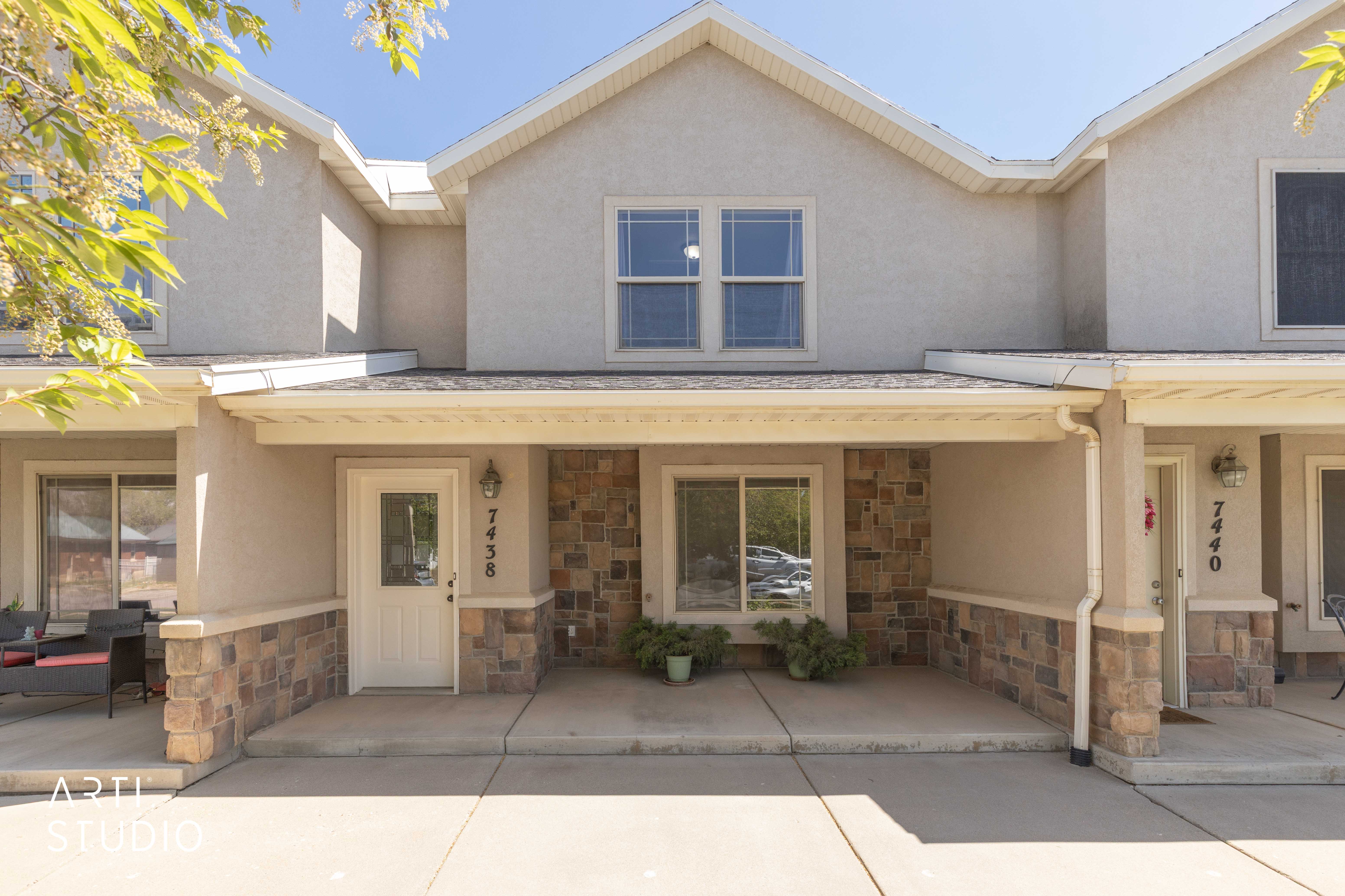 View of front of property with stone siding, covered porch, and stucco siding