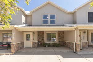 View of front of property with stone siding, covered porch, and stucco siding