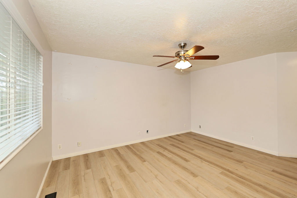 Unfurnished room with a textured ceiling, light wood finished floors, and ceiling fan