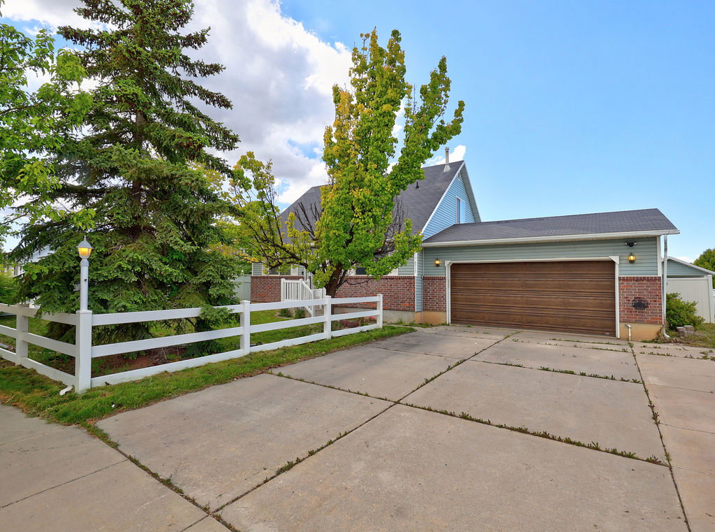 View of front facade featuring a fenced front yard, brick siding, concrete driveway, and a garage