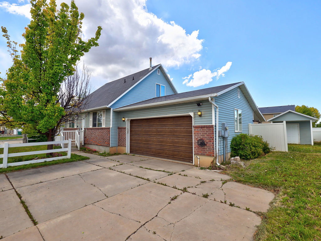 View of front of property with an attached garage, brick siding, concrete driveway, and a shingled roof