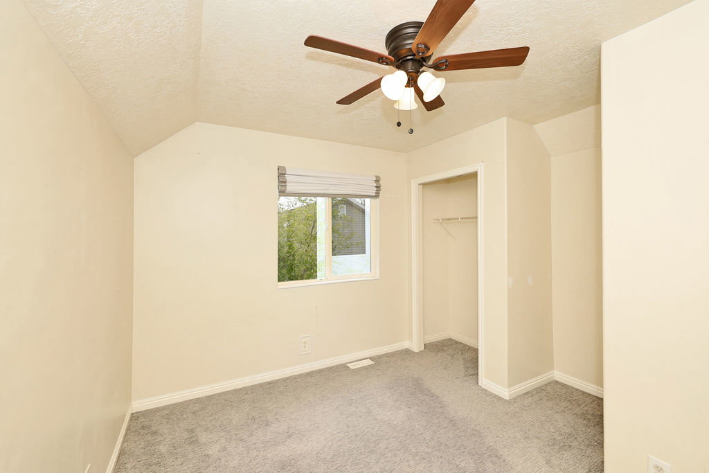 Unfurnished bedroom featuring light carpet, a closet, and a ceiling fan