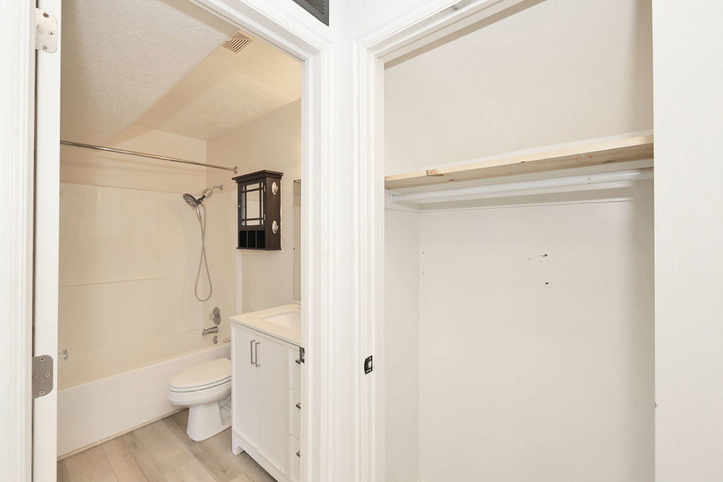 Bathroom with vanity, light wood-style floors, washtub / shower combination, and a textured ceiling