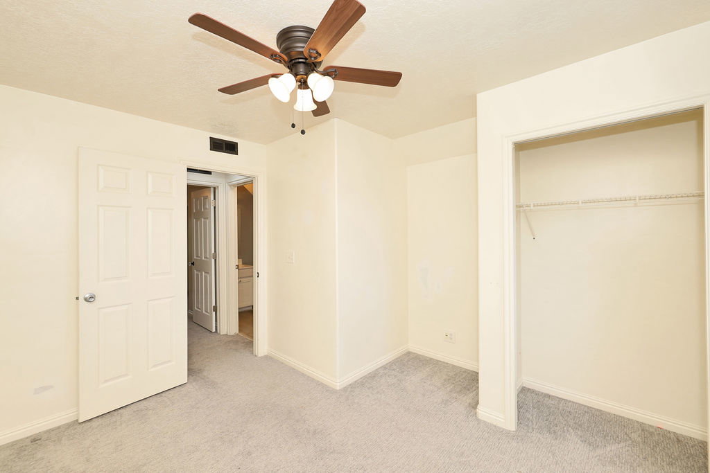 Unfurnished bedroom with light colored carpet, a ceiling fan, and a closet
