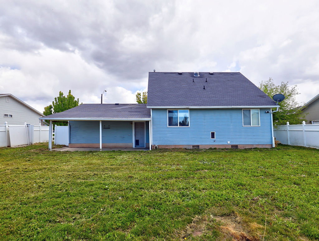 Back of house featuring a fenced backyard, a patio area, and a shingled roof