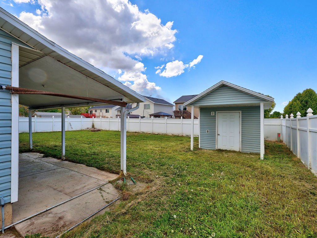 Fenced backyard featuring a storage unit