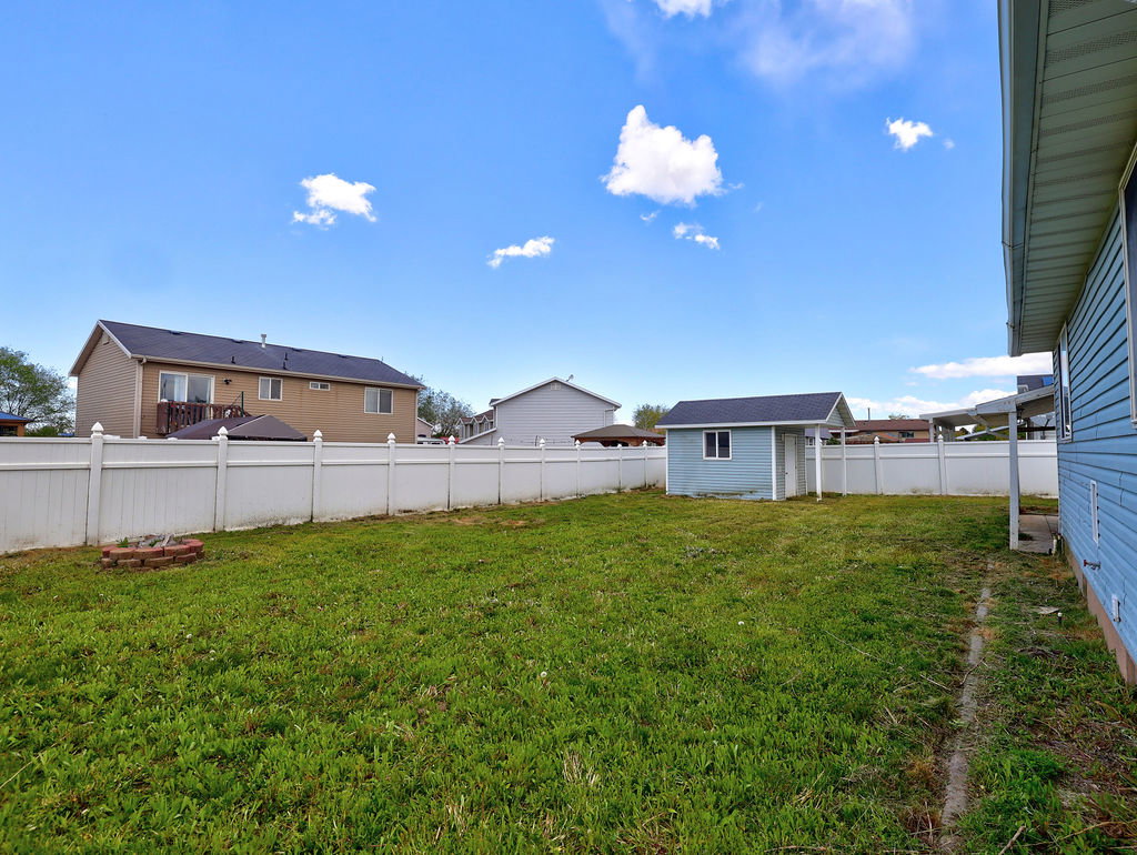 Fenced backyard featuring an outdoor structure