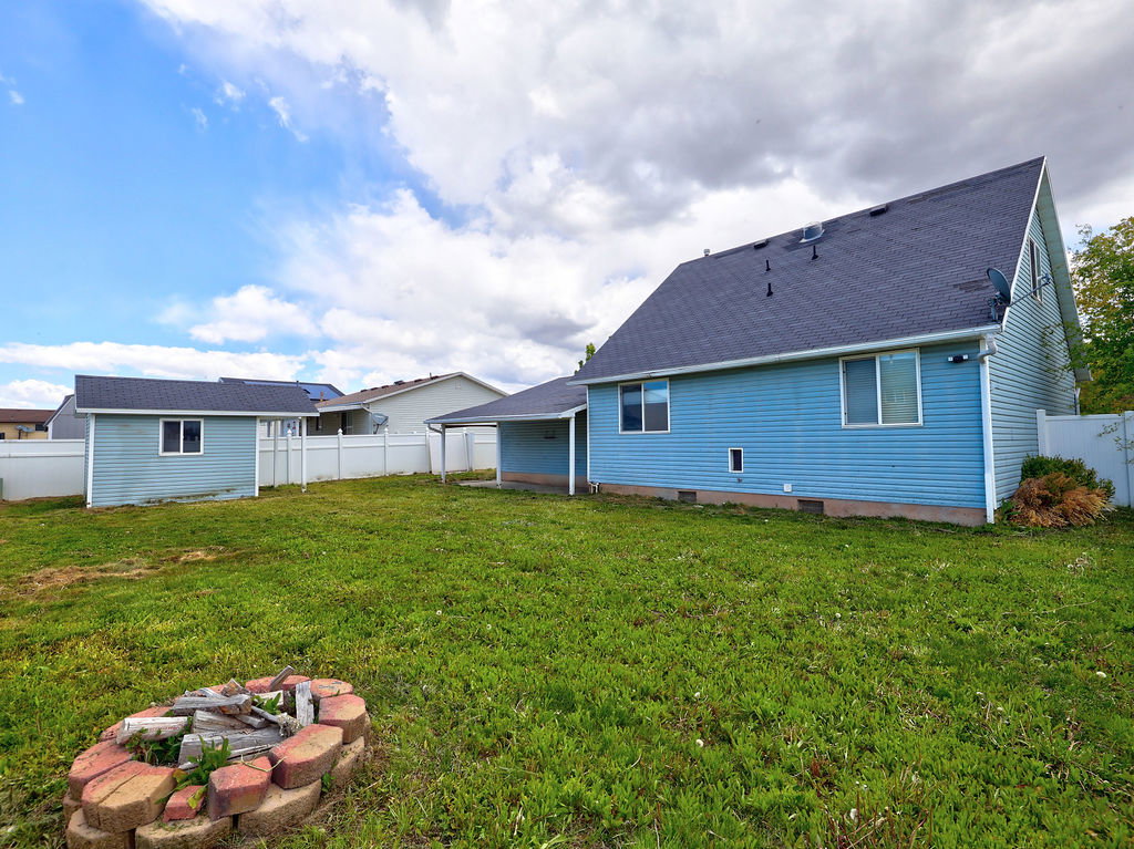 Back of house with a fenced backyard, roof with shingles, crawl space, and an outdoor fire pit