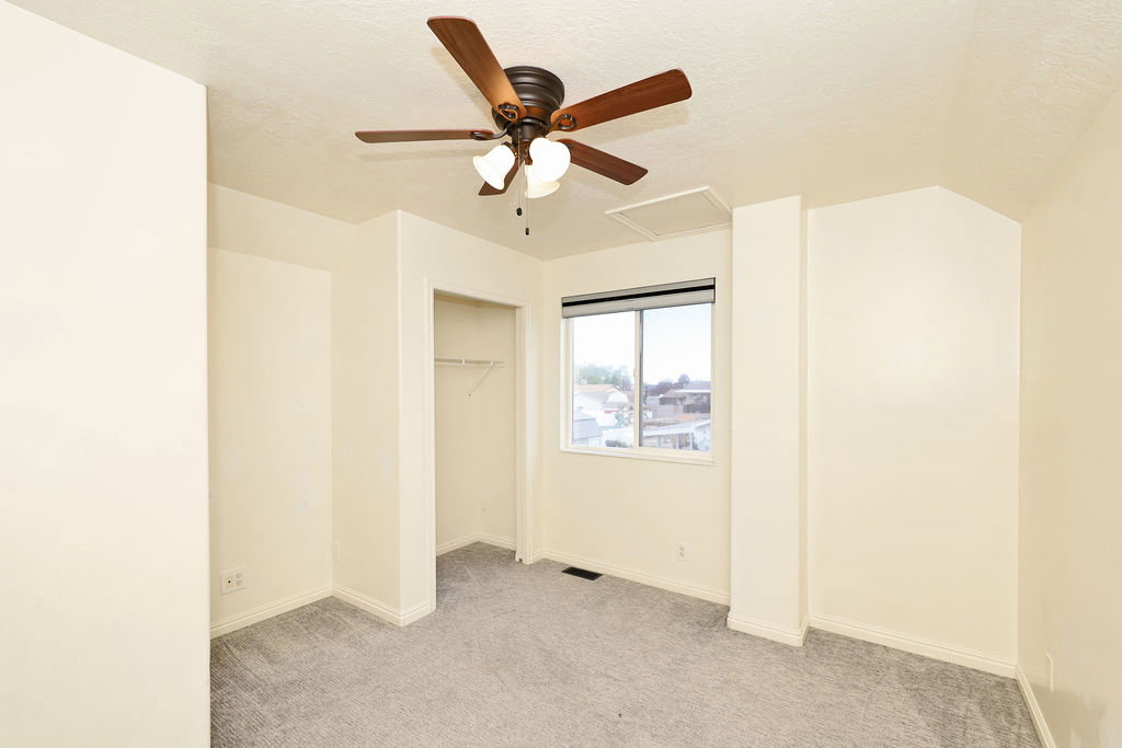 Unfurnished bedroom featuring light colored carpet, a ceiling fan, a closet, and a textured ceiling