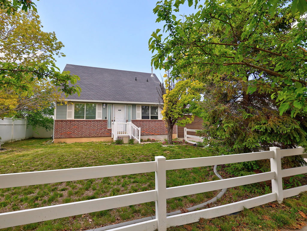 Bungalow-style home with a fenced front yard, brick siding, and roof with shingles