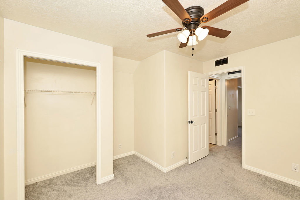 Unfurnished bedroom with light colored carpet, a textured ceiling, ceiling fan, and a closet