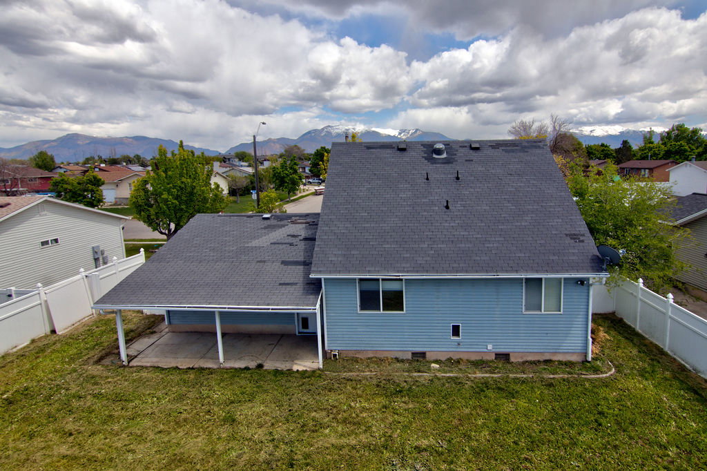 Back of house featuring crawl space, a fenced backyard, roof with shingles, and a residential view