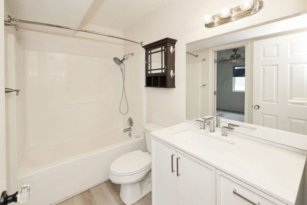 Bathroom with vanity, tub / shower combination, light wood-style floors, and a ceiling fan