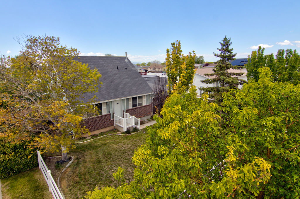 Back of house featuring a shingled roof, a lawn, and brick siding