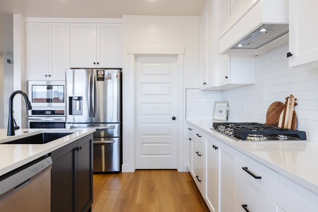 White kitchen featuring shaker cabinetry, stainless steel appliances, a black basin sink with a matte black faucet, gas range, and wood-finish flooring
