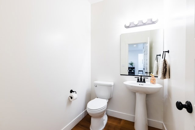 Pedestal sink with a matte black faucet, wall-mounted mirror, and vanity light fixture