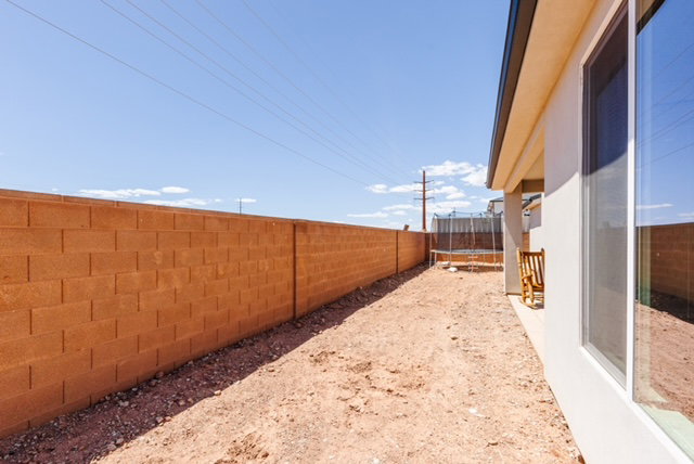 Expansive side yard featuring a block wall, bare earth, a recessed patio area, and large windows