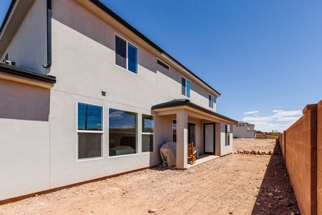 Rear exterior featuring a covered patio, multiple windows, and a block wall