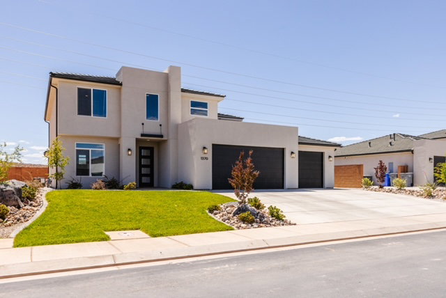 Contemporary stucco exterior with a flat roofline, featuring a three-car garage with black doors