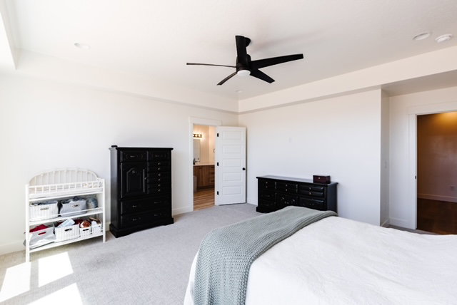 Spacious room featuring light-colored carpeting, a black ceiling fan, and recessed lighting