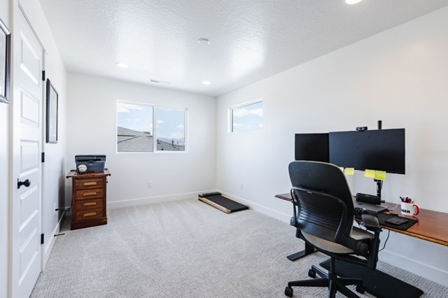Carpeted room with white walls and recessed ceiling lighting