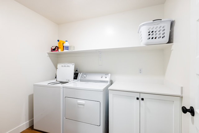 Dedicated laundry area featuring white cabinetry, a built-in countertop, and an overhead storage shelf