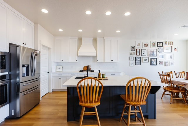 Kitchen featuring wood-finish flooring, white cabinetry, integrated stainless steel appliances, a center island with a white countertop, and recessed lighting