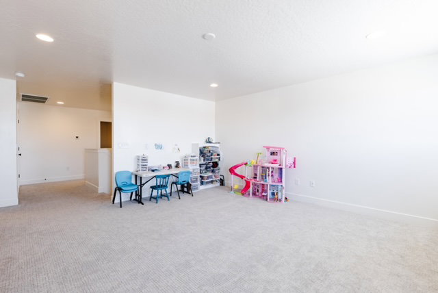 Expansive carpeted room featuring recessed lighting, light-colored walls, ample floor space, and a half-wall partition