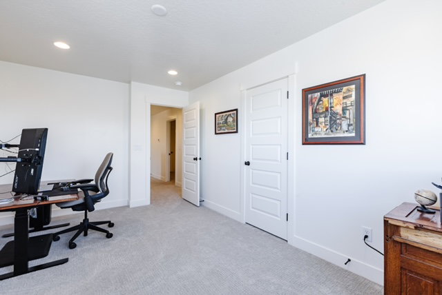 Spacious room featuring light-colored carpet flooring, white walls, and recessed lighting
