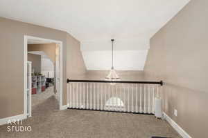 Corridor with carpet flooring and lofted ceiling