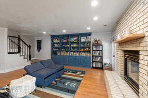 Living area featuring light wood finished floors, recessed lighting, and a brick fireplace