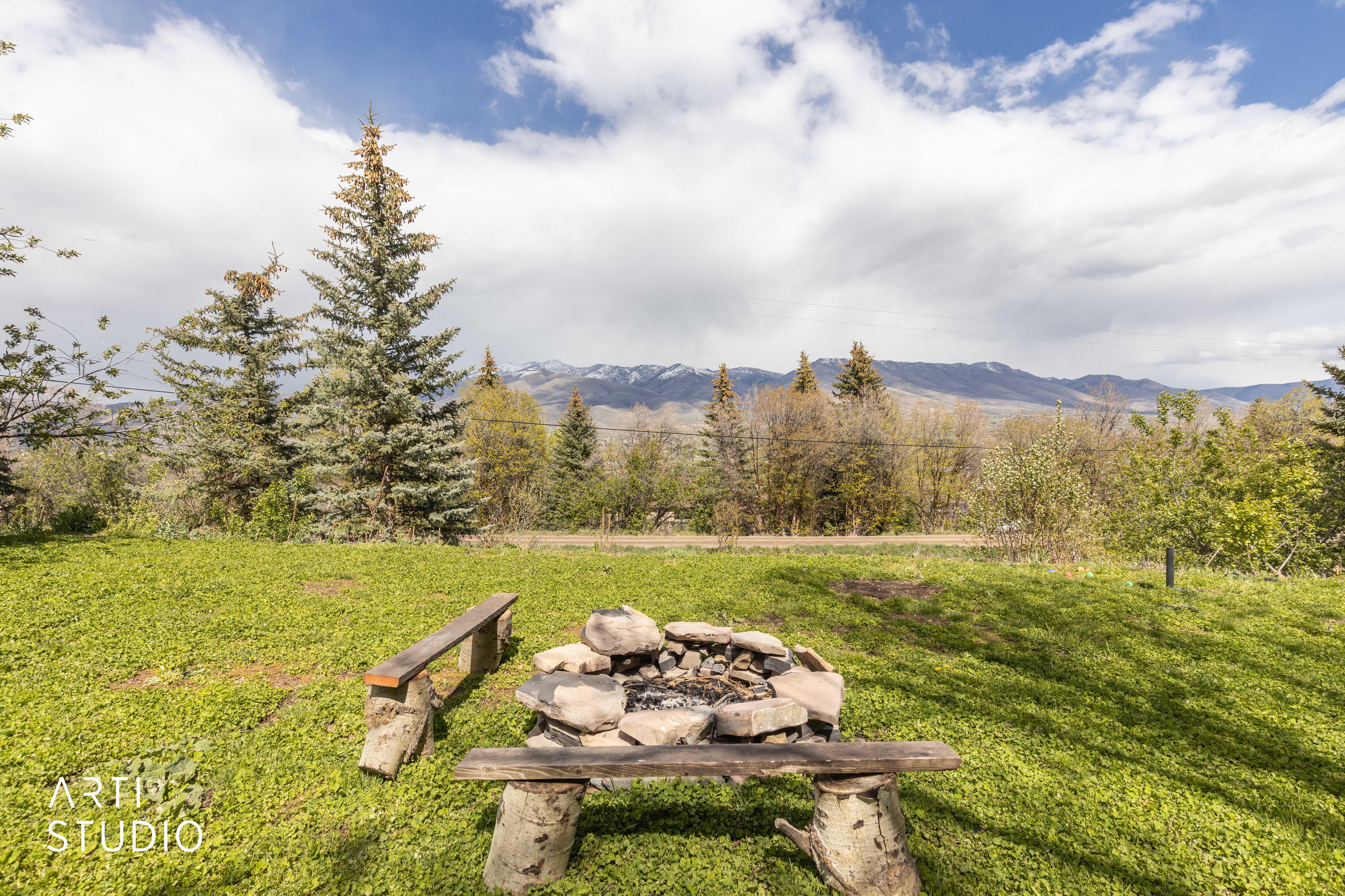 View of green lawn featuring an outdoor fire pit and a mountain view
